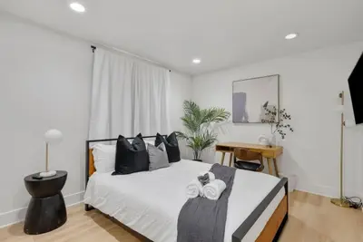 a bedroom with a bed with white sheets and black pillows at Modern Elegance- Big Group - Games - Sleeps 10 in Los Angeles