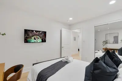 a white bedroom with a bed and a mirror at Modern Elegance- Big Group - Games - Sleeps 10 in Los Angeles