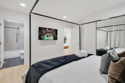 a bedroom with a large bed and a bathroom at Modern Elegance- Big Group - Games - Sleeps 10 in Los Angeles