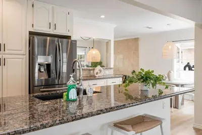 a kitchen with a stainless steel refrigerator and granite counter tops at Stunning Retro Beach Oasis, Dual Living, Pool in Long Beach
