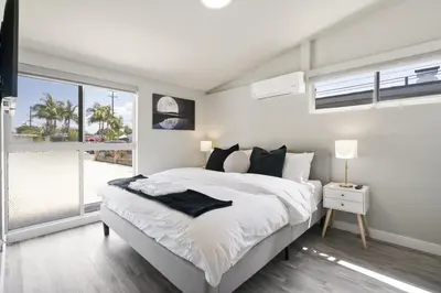 a white bedroom with a large bed and a window at Galactic Getaway Close to Disney with Pool and Games in Anaheim