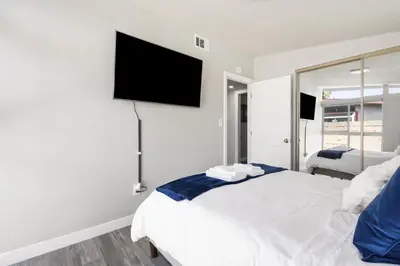 a bedroom with a white bed and a flat screen tv at Galactic Getaway Close to Disney with Pool and Games in Anaheim