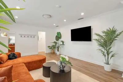 a living room with a couch and a tv on a wall at Refreshing Escape- Hot Tub- Games- Sleeps 10 in Long Beach