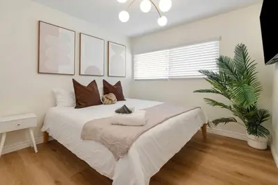 a bedroom with a large white bed and a plant at Trendy Getaway - Hot Tub - Putt Putt - Games in Long Beach