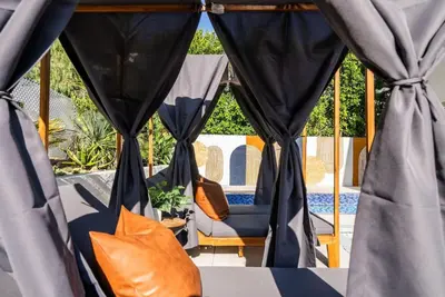 a room with blue curtains and a chair and a table at 2-Story Sanctuary - Spacious Hot Tub - Billiards in Los Angeles