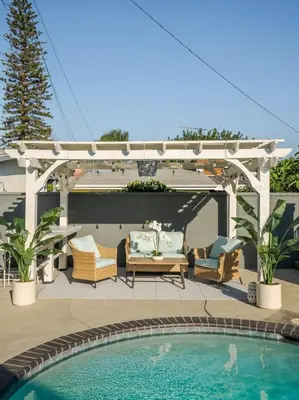 a patio with a pool and a pergola with chairs and a table at Coastal Lagoon - Pool Heating - Games - Air Hockey in Long Beach