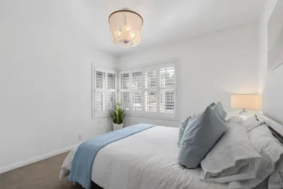 a white bedroom with a bed and a chandelier at Coastal Lagoon - Pool Heating - Games - Air Hockey in Long Beach