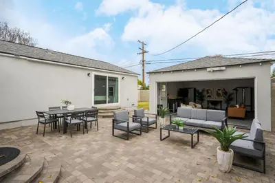 a patio with a couch and tables and chairs at Luxury Hangout - Private Spa - Game Room - Arcade in Long Beach