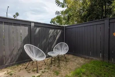 two white chairs sitting next to a fence at HGTV Featured Modern Craftsman Mins2Beach GameRm in Long Beach