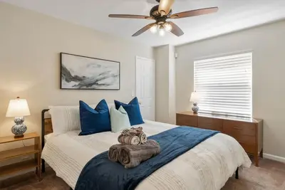 a bedroom with a bed with blue pillows and a ceiling fan at Surfers Dreams - 5min Drive to Beach with PoolTable in Long Beach