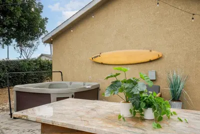 a yellow surfboard on the side of a building with a table and a table at Surfers Dreams - 5min Drive to Beach with PoolTable in Long Beach
