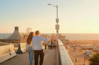 a man and a woman standing on a ledge overlooking a beach at 3BR Apartment Near Santa Monica Pier in Los Angeles