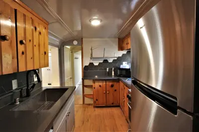 a kitchen with a stainless steel refrigerator and wooden cabinets at The Train Getaway Big Bear Lake in Big Bear Lake