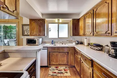 a kitchen with wooden cabinets and a sink and a window at Stunning Deck Views Cozy Running Springs Cabin in Running Springs