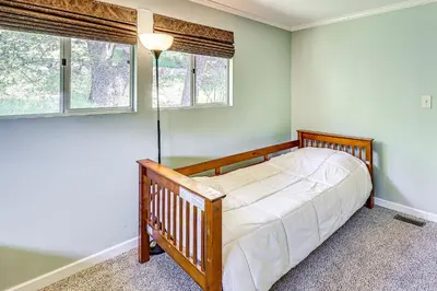 a bedroom with a crib and two windows at Stunning Deck Views Cozy Running Springs Cabin in Running Springs