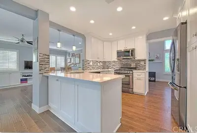 a large kitchen with white cabinets and a refrigerator at Mountain View • Pool House in Chino Hills