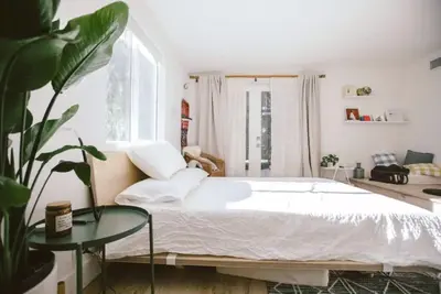 a bedroom with a large white bed and a plant at Private and Quiet Los Feliz Guest Suite with VIEWS in Los Angeles