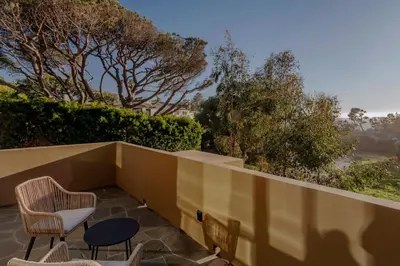 a patio with two chairs and a table and some trees at Private Malibu Escape - Walk to Secluded Beach in Malibu