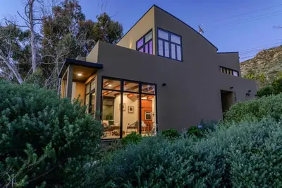a house with large glass doors on a hill at Private Malibu Escape - Walk to Secluded Beach in Malibu