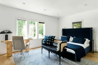 a bedroom with a bed and a chair and windows at Luxury Melrose District 3BR Retreat Pool Spa Gym in Los Angeles