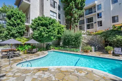 a swimming pool with a table and chairs and a building at Westwood UCLA 2BR, 1BA Cozy Condo w Amenities in Los Angeles