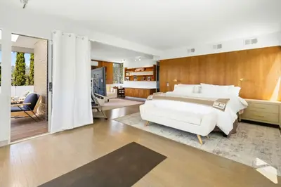 a bedroom with a large white bed and a living room at Hilltop Designer Midcentury Modern 4BR Pool HotTub in Los Angeles