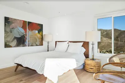 a white bedroom with a bed and a painting on the wall at Luxe Malibu Retreat - Ocean Views, Hot Tub and Gym in Malibu