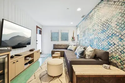 a living room with a couch and a tv at Lux by Manhattan Beach Pier and Panoramic Ocean View in Manhattan Beach