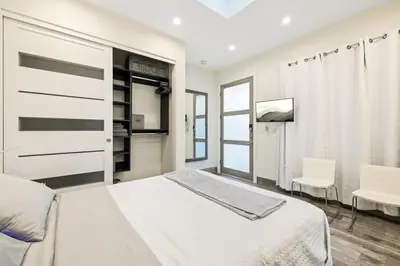 a white bedroom with a bed and a chair at Private Designer Home in West Hollywood in Los Angeles