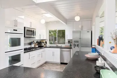 a large white kitchen with white cabinets and appliances at Eichler Mid-Century Perfect WFH, Relax and Entertain in Orange