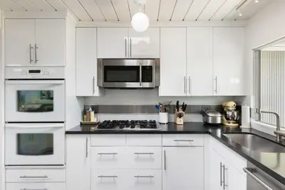 a kitchen with white cabinets and a stove top oven at Eichler Mid-Century Perfect WFH, Relax and Entertain in Orange