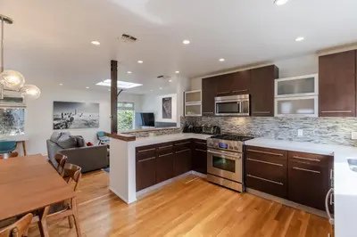 a kitchen with wooden cabinets and a dining room at Heart of Venice Designer Home Near Abbot Kinney in Los Angeles