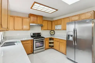 a kitchen with wooden cabinets and a stainless steel refrigerator at Russell House Near Hollywood & Griffith Park home in Los Angeles