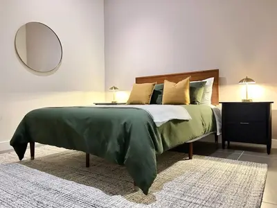 a bedroom with a large green bed with a mirror at DTLA 2BR Loft with Hot Tub & Rooftop Pool! in Los Angeles