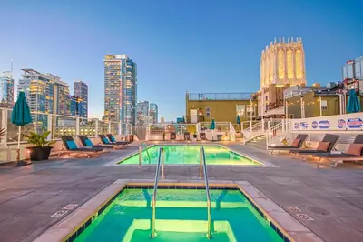 a swimming pool with chairs and a city skyline at DTLA 2BR Loft with Hot Tub & Rooftop Pool! in Los Angeles