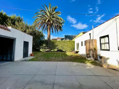 a palm tree in front of a white building at Tranquil Comfortable 2BR Home Mid Wilshire in Los Angeles