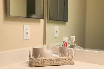 a bathroom sink with a basket of toiletries in front of a mirror at Luxe Homestay In Venice in Los Angeles