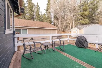 a patio with chairs and a table on a deck at The Quiz Cottage Games & BBQ Outdoor Area! in Big Bear Lake