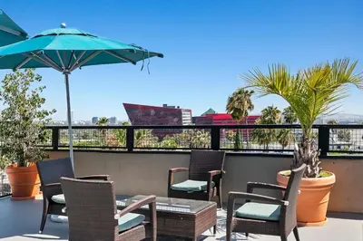 a patio with chairs and a table and an umbrella at Skyline Escape 1-Bedroom with Balcony and Roof-Top Pool in Los Angeles