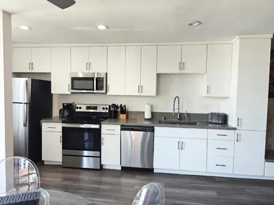 a kitchen with white cabinets and stainless steel appliances at Skyline Escape 1-Bedroom with Balcony and Roof-Top Pool in Los Angeles