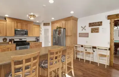 a kitchen with wooden cabinets and a kitchen island with bar stools at Moab Cozy Lane HotTub & Game Room with Pool Table in Big Bear Lake