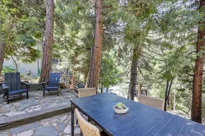 a blue table and chairs on a patio with trees at Walk to Lake Gregory Family Retreat with Patio! in Crestline