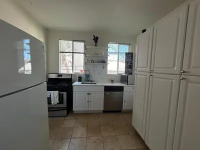 a kitchen with white cabinets and a sink and a stove at Hollywood Home in Los Angeles