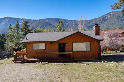 a small house with a porch and mountains in the background at Mountain-View Haven with Deck in Pine Mountain Club in Frazier Park