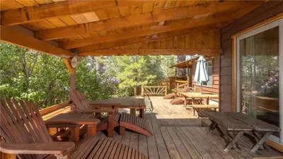 a wooden deck with wooden tables and chairs on a house at Hot Tub, Near Village/Lake - Kelly`s Kottage in Big Bear Lake