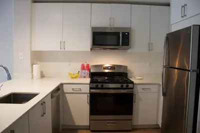 a kitchen with white cabinets and a stove and a microwave at Luxury 3 Bedroom Apartment in Santa Clarita
