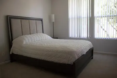 a bed in a bedroom with two windows at Luxury 3 Bedroom Apartment in Santa Clarita