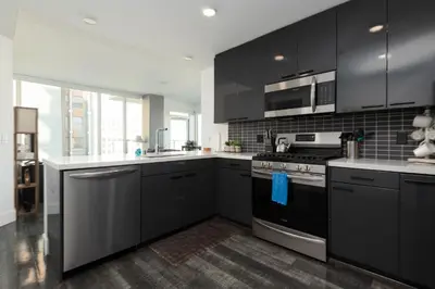 a kitchen with black cabinets and stainless steel appliances at 3-Bed High-Rise with Panoramic Views, Pool & Spa in Los Angeles