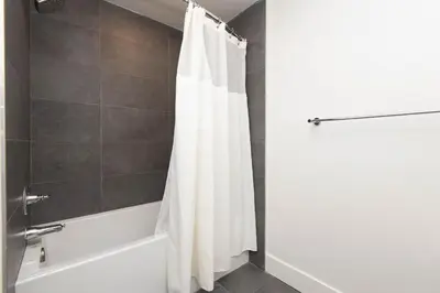 a bathroom with a white shower curtain and a tub at By The Coast Living in Santa Monica Pier Promenade in Los Angeles