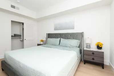 a white bedroom with a large bed and a mirror at By The Coast Living in Santa Monica Pier Promenade in Los Angeles